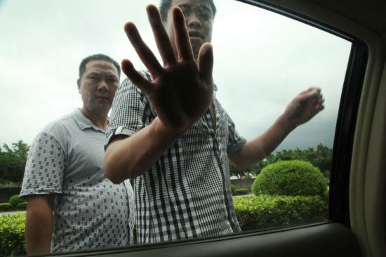 围堵记者的保安拍打车窗。